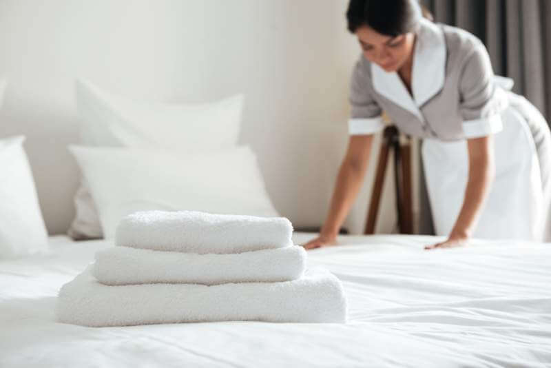 young-hotel-maid-setting-up-pillow-on-bed