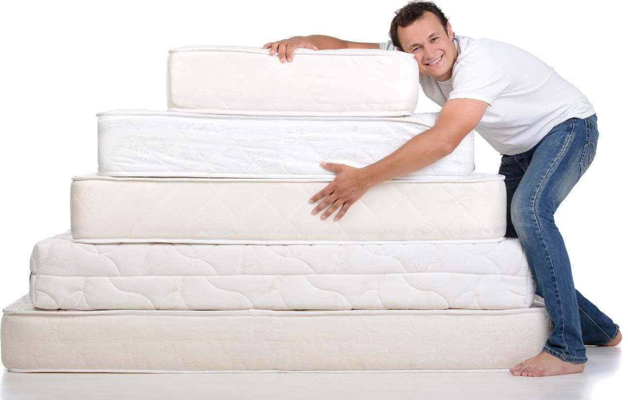Funny man in pajamas sitting on lots of mattresses